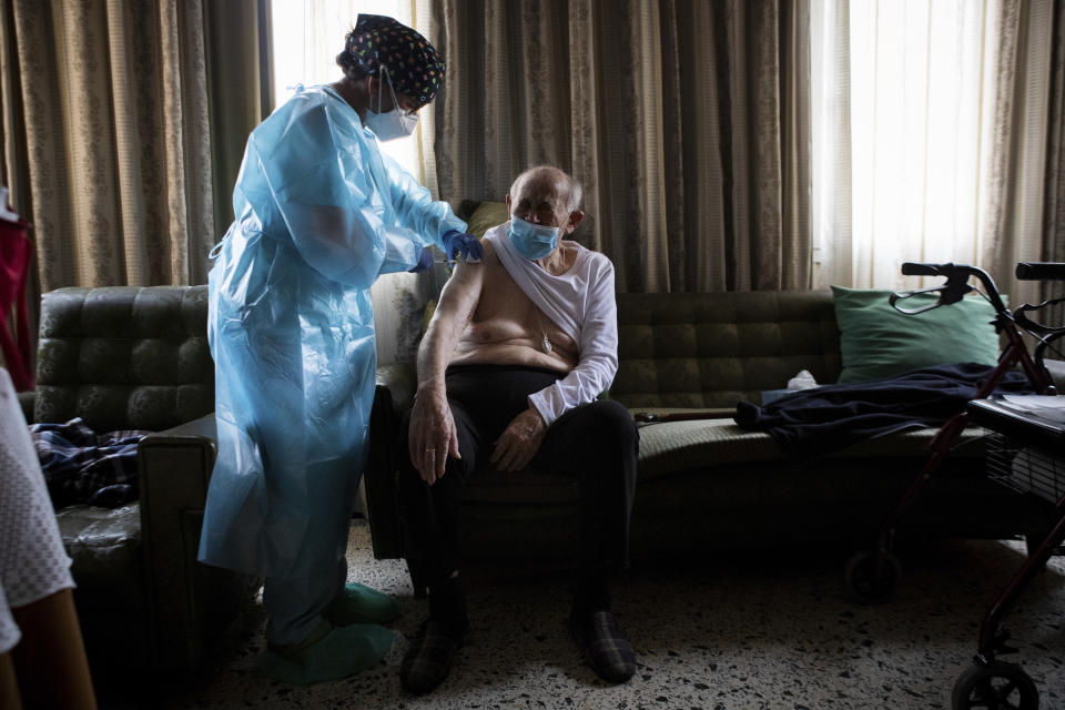 Nurse Pilar Rodríguez administers the COVID-19 vaccine to her patient Rafael Capo Frau, 92, at his home in the town of Sa Pobla on the Spanish Balearic Island of Mallorca, Spain, Friday, April 30, 2021. Spain has set the goal of vaccinating 70% of its adult population - some 33 million people - by the end of August. After being slowed by delays in shipments by drug makers, Spain has sped up its vaccination efforts and now has at least one shot in 12 million people. (AP Photo/Francisco Ubilla)