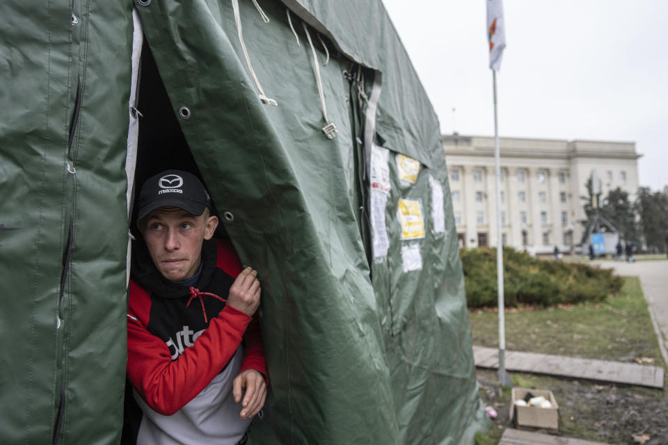 A young man peeks out of a heating tent, a “Point of Invincibility,” a government-built help station, in Kherson, Ukraine, Saturday, Dec. 3, 2022. (AP Photo/Evgeniy Maloletka)