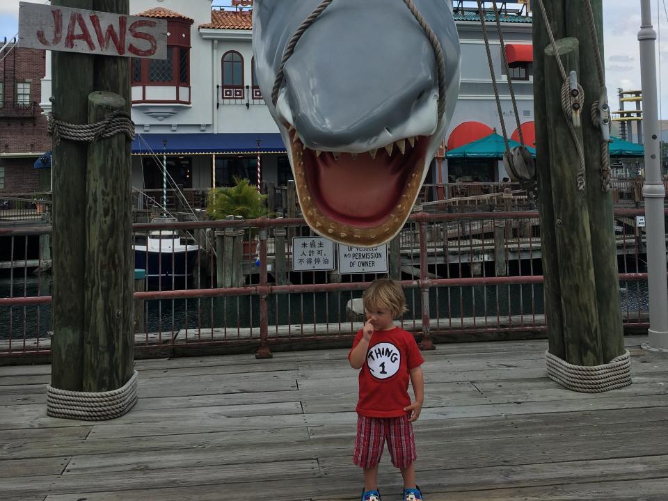 toddler standing under a jaws statue at universal studios