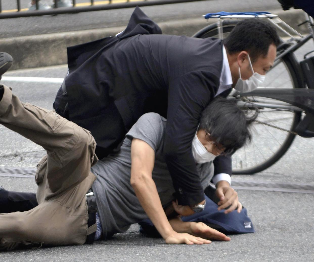 Tetsuya Yamagami, bottom, is detained after the shooting on Friday.