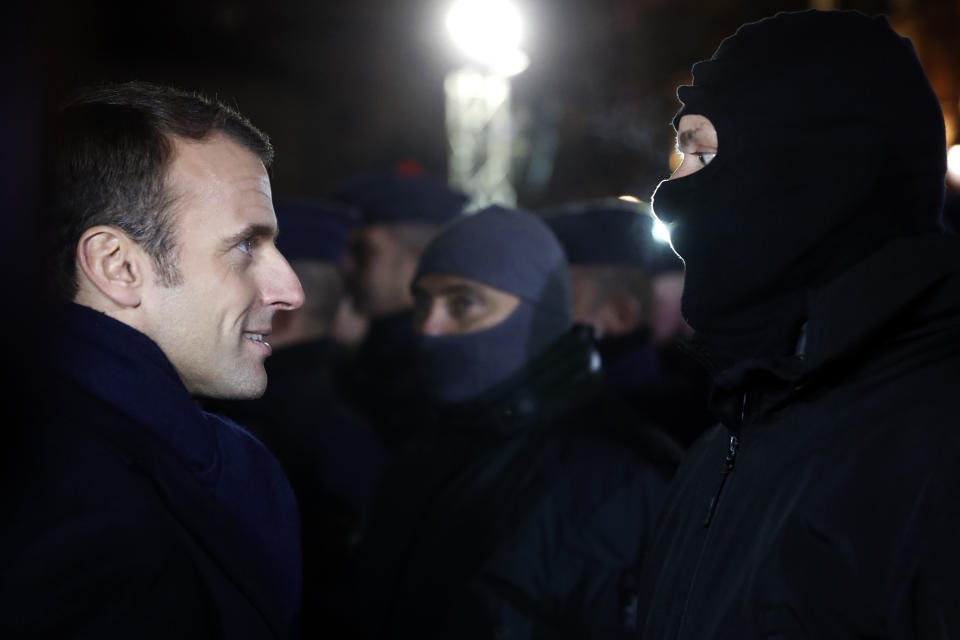 French President Emmanuel Macron meets police officers wearing hoods near the Christmas market in Strasbourg, eastern France, Friday, Dec.14, 2018. A fourth person died Friday from wounds suffered in an attack on the Christmas market in Strasbourg, as investigators worked to establish whether the main suspect had help while on the run. (AP Photo/Jean-Francois Badias, Pool)