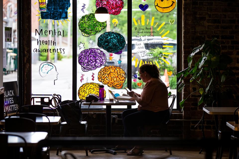 A person works on a laptop and cellphone inside The Slow Down Coffee Co.