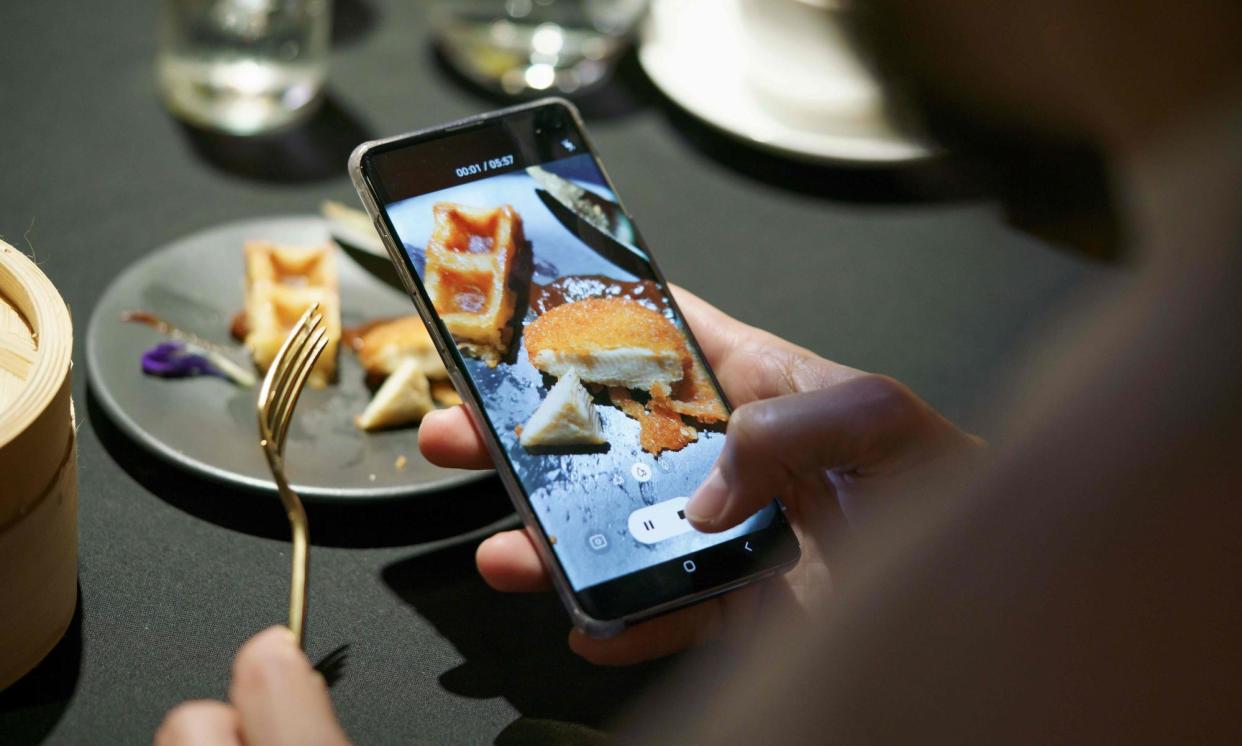 <span>A guest uses a mobile phone to take a video of a meal featuring a nugget made from lab-grown chicken meat during a media presentation in Singapore on 22 December 2020.</span><span>Photograph: Nicholas Yeo/AFP/Getty Images</span>