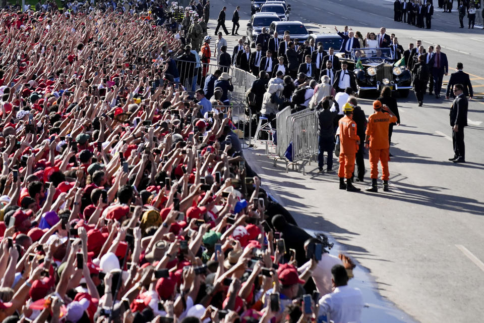 Supporters wave as Luiz Inacio Lula da Silva arrives on an open car to the Planalto Palace after he was sworn in as new president in Brasilia, Brazil, Sunday, Jan. 1, 2023. (AP Photo/Silvia Izquierdo)