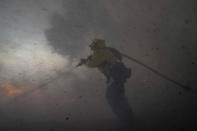 A firefighter battles the Silverado Fire Monday, Oct. 26, 2020, in Irvine, Calif. A fast-moving wildfire forced evacuation orders for 60,000 people in Southern California on Monday as powerful winds across the state prompted power to be cut to hundreds of thousands to prevent utility equipment from sparking new blazes. (AP Photo/Jae C. Hong)