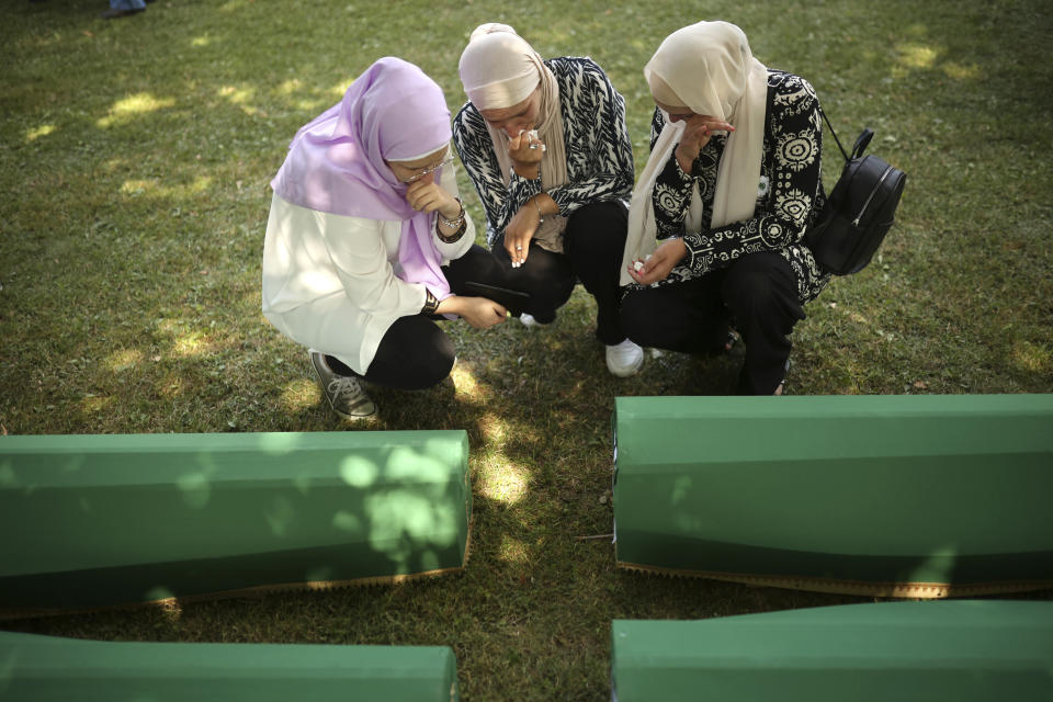 Bosnian muslim women mourn next to the coffin containing remains of their family member who is among 50 newly identified victims of Srebrenica Genocide in Potocari, Monday, July 11, 2022. Thousands converge on the eastern Bosnian town of Srebrenica to commemorate the 27th anniversary on Monday of Europe's only acknowledged genocide since World War II. (AP Photo/Armin Durgut)