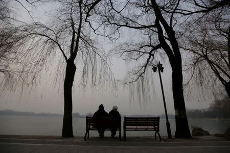 An elderly couple sit beside a lake in smog on a polluted day as a red alert issued for air pollution in Beijing, China December 17, 2016. REUTERS/Jason Lee