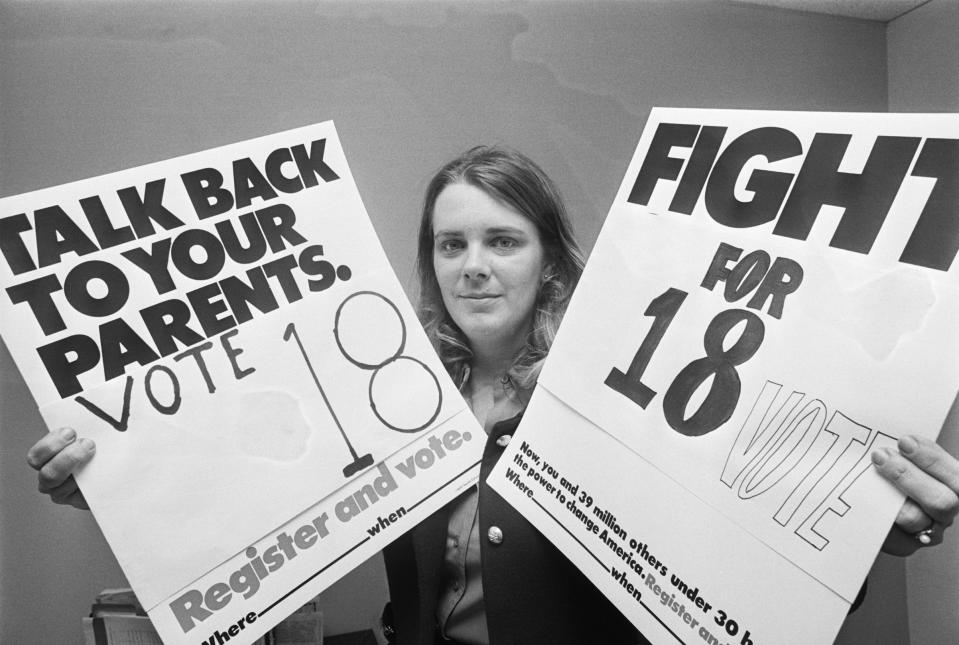 Patricia Keefer at her office in Washington, D.C. in 1971, holding up placards urging 18-year-olds (who have just received to right to vote) to use their power and vote.