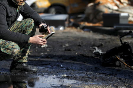 A Syrian army soldier uses his mobile phone as he inspects the site of a suicide bombing at a police officers' club in a residential district of Damascus, in Masaken Barza, Syria February 9, 2016. REUTERS/Omar Sanadiki