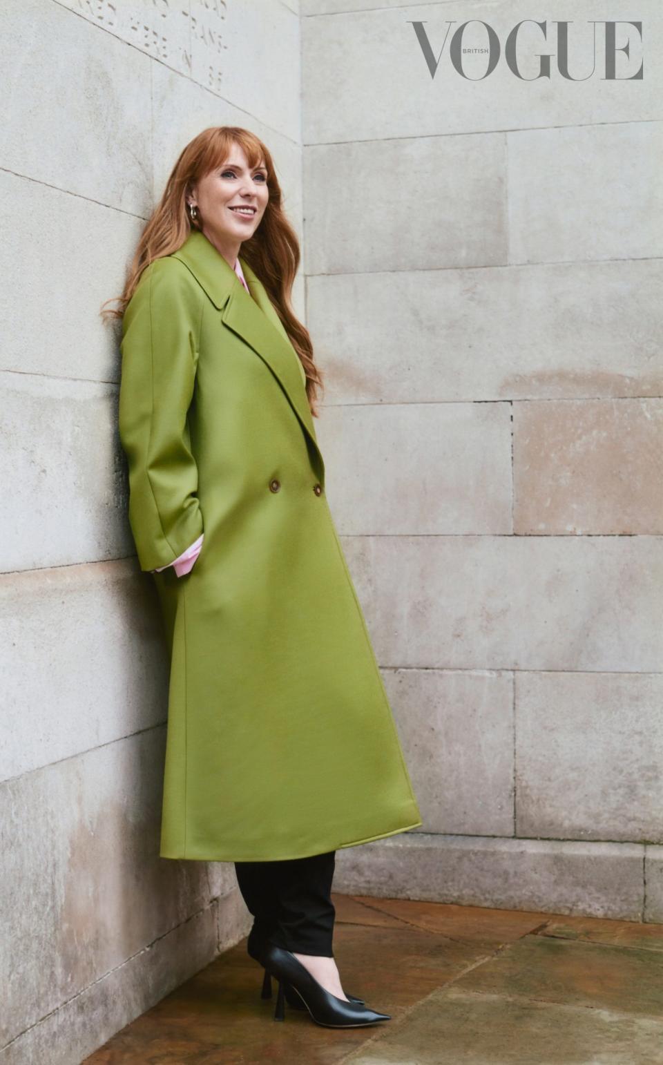 Angela Rayner in a light olive coat standing against the wall for British Vogue