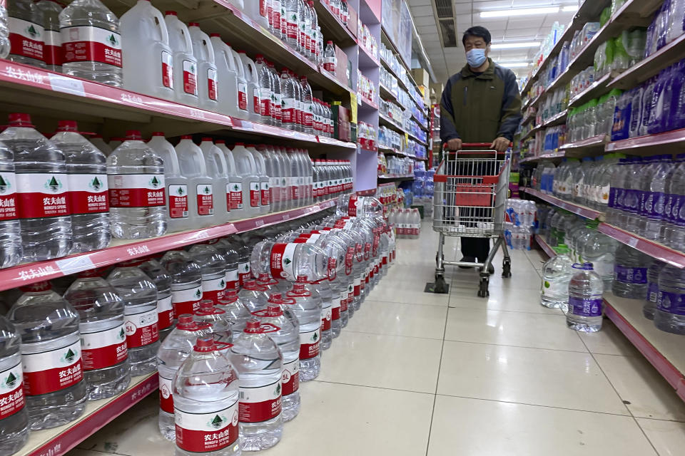 A man wearing a mask passes rows of bottled water at a supermarket in Beijing, China, Wednesday, Nov. 3, 2021. A recent seemingly innocuous government recommendation for Chinese people to store necessities for an emergency quickly sparked scattered instances of panic-buying and online speculation of imminent war with Taiwan. (AP Photo/Ng Han Guan)
