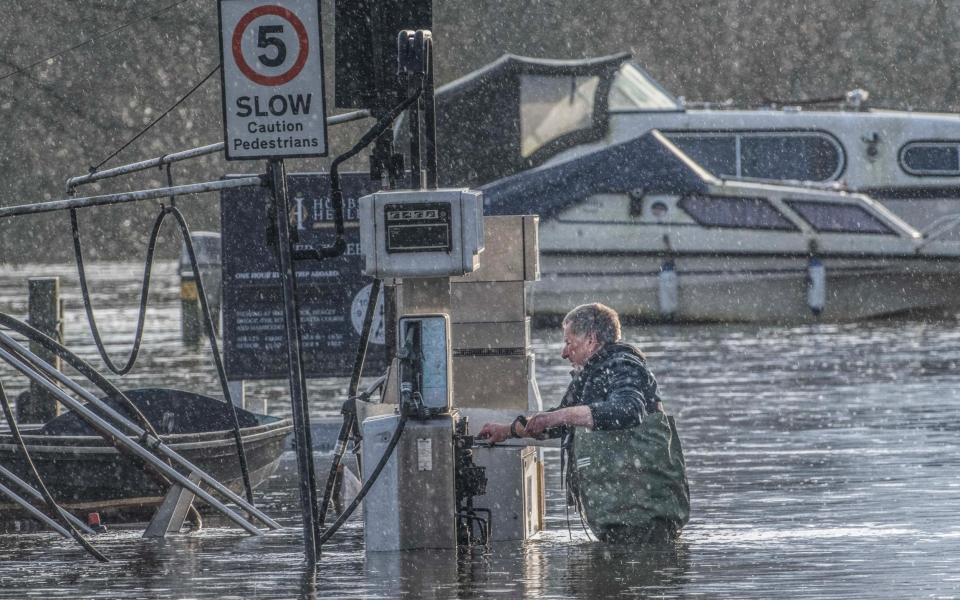 A man examines his submerged fuel pump at Henley-on Thames in Oxfordshire