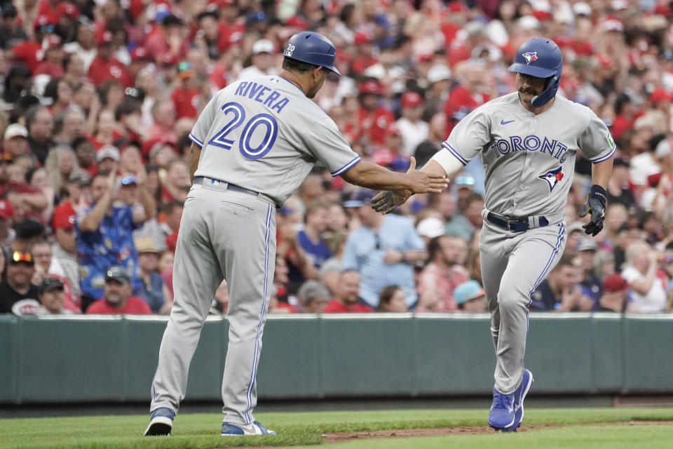 Toronto Blue Jays' Davis Schneider, right, celebrates with third base coach Luis Rivera after hitting a solo home run against the Cincinnati Reds during the fifth inning of a baseball game Saturday, Aug. 19, 2023, in Cincinnati. (AP Photo/Joshua A. Bickel)