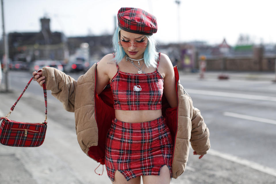 Influencer y creadora de contenido Naomi Jon con una chaqueta de pana marrón claro de Karl Kani, una boina de tartán roja de Ouchhh Store, una bolsa de tartán roja de Ouchhh Store, un top corto de tartán rojo con Hello Kitty de Ouchhh Store , una minifalda de tartán rojo de Ouchhh Store, botas negras sobre la rodilla de Demonia y gafas de sol cuadradas transparentes teñidas de rosa de Jaded London. (Foto de Streetstyleshooters / Getty Images)