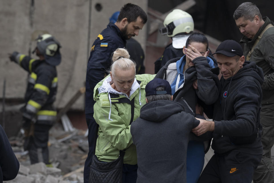 Relatives and friends comfort a woman after Ukrainian rescue workers found a body of a person under the debris following a Russian attack that heavily damaged a school in Mykolaivka, Ukraine, Wednesday, Sept. 28, 2022. (AP Photo/Leo Correa)