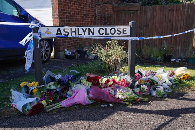 Bouquets of flowers underneath a street sign saying Ashlyn Close