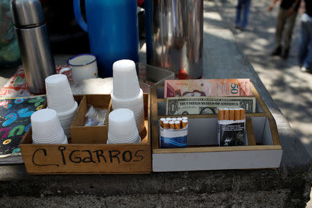 A U.S. dollar and Venezuelan bolivar notes are seen next to cigarettes on sale during an ongoing blackout in downtown Caracas, Venezuela March 10, 2019. REUTERS/Marco Bello