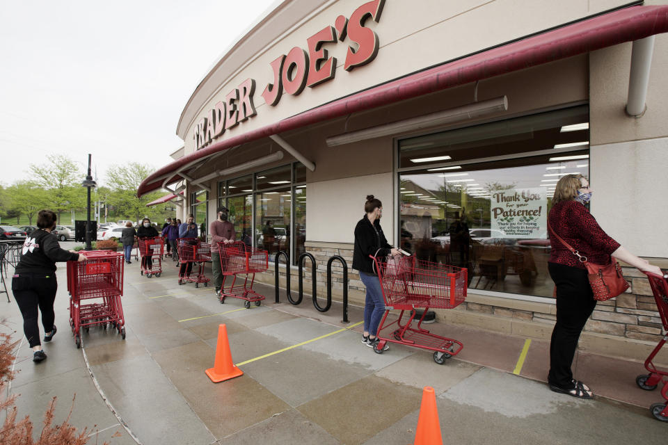 FILE - Customers observe social distancing as they wait to be allowed to shop at a Trader Joe's supermarket in Omaha, Neb., May 7, 2020. Millions of workers whose jobs don’t provide paid sick days are having to choose between their health and their paycheck as the omicron variant of COVID-19 rages across the nation. While many companies instituted more robust sick leave policies at the beginning of the pandemic, those have since been scaled back with the rollout of the vaccines, even though the omicron variant has managed to evade them. (AP Photo/Nati Harnik, File)
