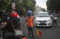 A parking attendant covers his head with a water bottle amid the coronavirus outbreak, in Yogyakarta, Indonesia, Friday, April 17, 2020. (AP Photo/Fahmi Rosyidih)