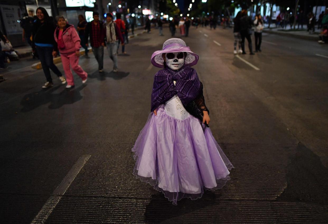 Une jeune fille déguisée en "catrina" participe au défilé à Mexico pour célébrer le jour des morts. <a href="https://www.gettyimages.com/detail/news-photo/girl-dressed-as-catrina-walks-while-taking-part-in-the-news-photo/617638204?adppopup=true" rel="nofollow noopener" target="_blank" data-ylk="slk:Yuri Cortez/AFP via Getty Images;elm:context_link;itc:0;sec:content-canvas" class="link ">Yuri Cortez/AFP via Getty Images</a>