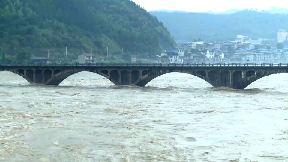 Floodwaters climbing up the pillars of a bridge. - CCTV