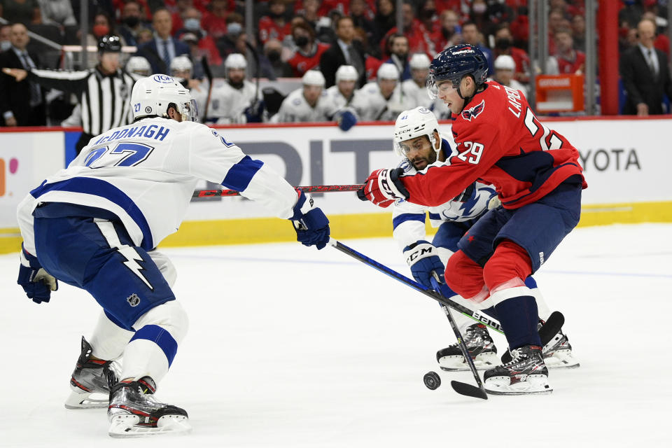 Washington Capitals center Hendrix Lapierre (29) battles for the puck against Tampa Bay Lightning defenseman Ryan McDonagh (27) and Pierre-Edouard Bellemare (41) during the first period of an NHL hockey game, Saturday, Oct. 16, 2021, in Washington. (AP Photo/Nick Wass)