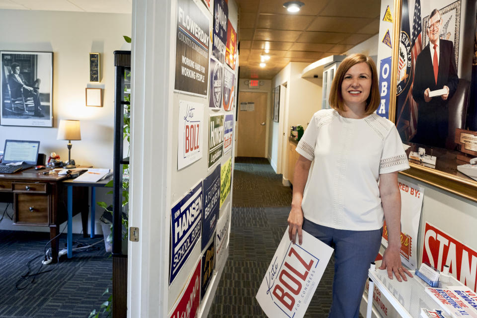 In this June 22, 2020, photo, Kate Bolz, Democratic candidate for Nebraska's 1st Congressional District, poses for a photo among election placards and the photos of President John F. Kennedy, left, and Sen. Jim Exon, a Democrat who never lost an election, at the Lancaster County Democratic Party offices in Lincoln, Neb. State Democrats have taken a lot of proactive steps in recent years to try to expand the party and win elections, but with Democrats now accounting for 29% of the state's registered voters, running as a Democrat in Nebraska is tough. (AP Photo/Nati Harnik)