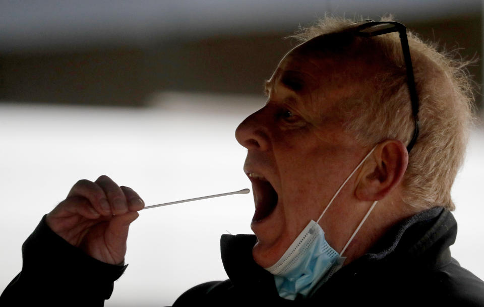 A man takes his own COVID-19 swab test at a newly set-up testing facility in a car park in West Ealing, London, Tuesday, Feb. 2, 2021. British health authorities plan to test tens of thousands of people in a handful of areas of England in an attempt to stop a new variant of the coronavirus first identified in South Africa spreading in the community. The Department of Health says a small number of people in England who had not travelled abroad have tested positive for the strain. (AP Photo/Frank Augstein)