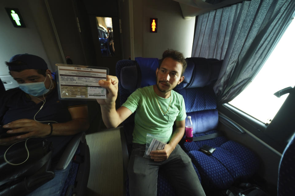 Gerado Garcia Navas, from Venezuela, shows his document that allows him to legally travel through Mexico, as he sits on a bus departing Huixtla, Chiapas state, Mexico, Friday, June 10, 2022. Navas is one of thousands of migrants who left Tapachula by foot at the start of the week, tired of waiting for normalize their status in a region with little work, with the ultimate goal of reaching the U.S. (AP Photo/Marco Ugarte)