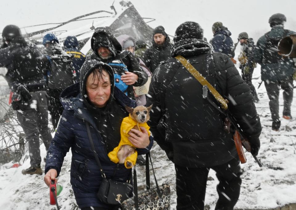 A woman carries her dog while evacuating Irpin as the snow falls. 