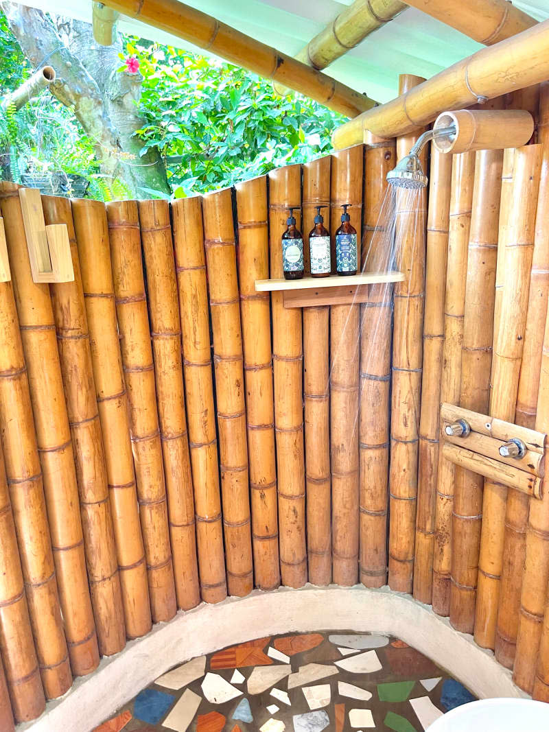 Outdoor shower in bamboo structure with metal roof.