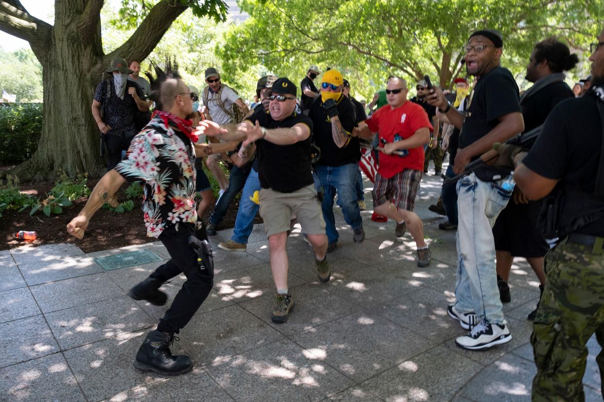 A member of the "boogaloo" movement, left, gets into a physical altercation with members of the Proud Boys