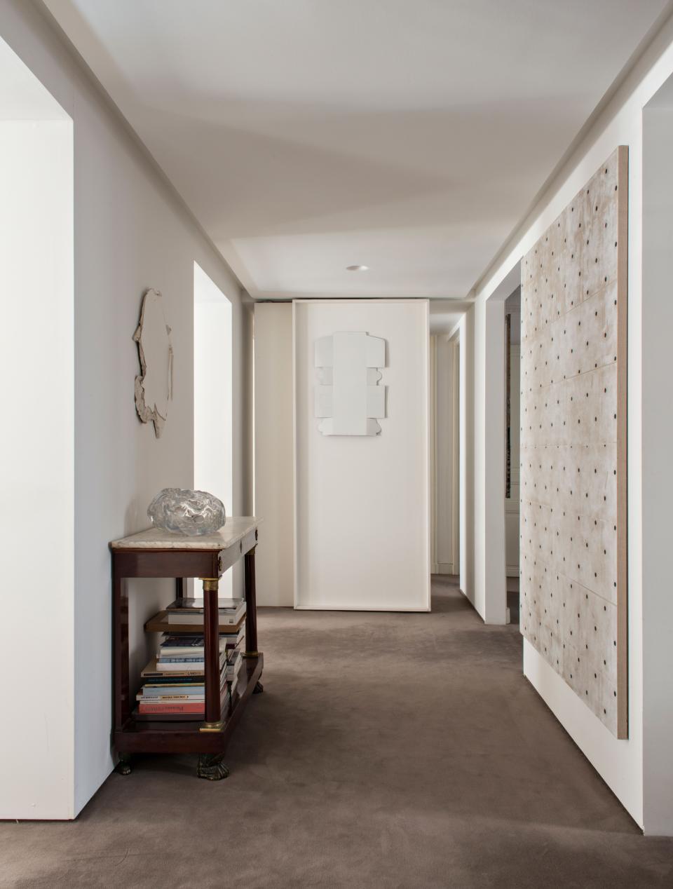 The apartment entrance is treated like a gallery with art hanging on all the walls. On the right hangs a painting by American artist Matt Sheridan Smith. On the back wall, which doubles as a sliding door, is Cake Box, a 2015 work by British artist Sylvan Lionni Totem. Sitting on a family console is a glass sculpture by Paris-born artist Flavie Audi. Above, a work by Welsh artist Cerith Wyn Evans can be seen. The wool carpet is from Codimat.