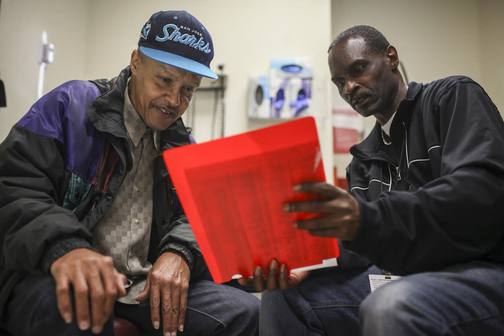 Community health worker Ron Sanders, right, helps a patient at San Francisco’s Southeast Family Health Center, part of the Transitions Clinic Network that assists former inmates navigate health care after release. (Courtesy of Transitions Clinic Network)