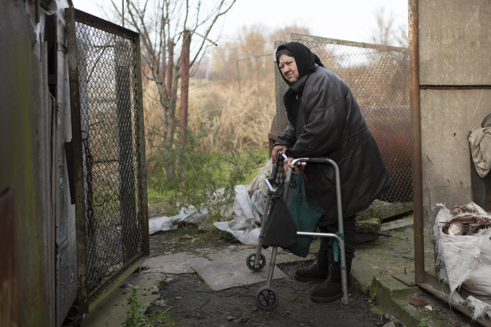 Olga Lehan, 71, walks in a yard of her house in the village of Demydiv, about 40 kilometers (24 miles) north of Kyiv, Ukraine, Tuesday, Nov. 2, 2022. Olga Lehan's home near the Irpin River was flooded when Ukraine destroyed a dam to prevent Russian forces from storming the capital of Kyiv just days into the war. Weeks later, the water from her tap turned brown from pollution. (AP Photo/Andrew Kravchenko)