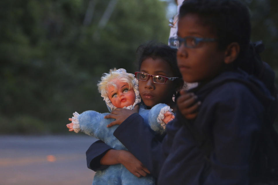 FILE - In this March 9, 2018 file photo, 9-year-old Ashley Angelina holds her doll as she hitch-hikes with her twin brother Angel David and parents after crossing the Venezuelan border in their migration to Brazil, near Pacaraima. Venezuelans began fleeing two decades ago, when revolutionary Hugo Chavez rose to power, in a familiar pattern: Those with money and connections fled first, often to the United States, while the poorer left later, by bus and on foot. (AP Photo/Eraldo Peres, File)