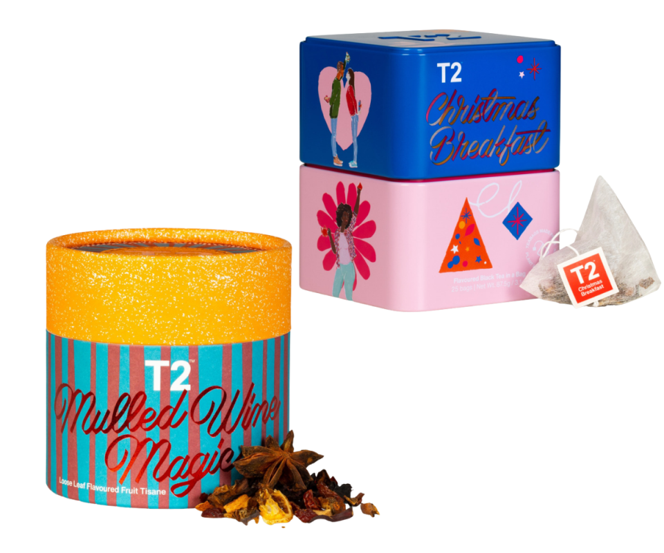 T2's limited-edition Christmas teas side by side: Left is the mulled wine magic loose-leaf tube with an orange lid and blue and red striped container. The top is a Christmas breakfast blend with a blue lid and pink bottom. Both sit against a white background.