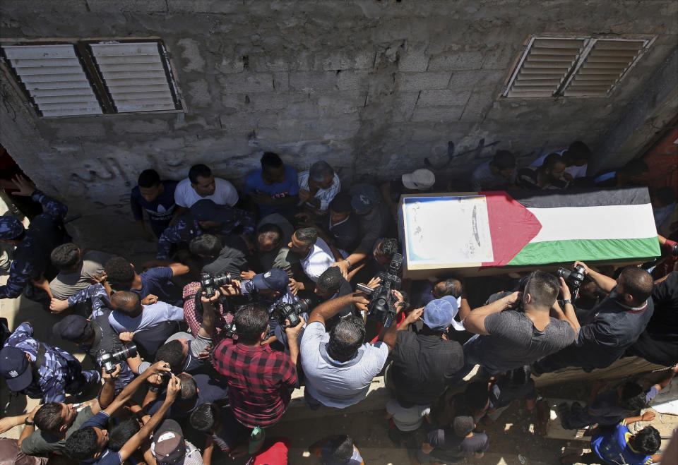 Palestinian mourners and police officers carry the coffin of 23-year-old pregnant mother Enas Khamash and her daughter Bayan, whose picture is on the coffin, during their funeral in Deir el-Balah, central Gaza Strip, Thursday, Aug. 9, 2018. Israeli warplanes have hit dozens of targets in the Gaza Strip, while Palestinian militants fired scores of rockets into Israel in a fierce burst of violence overnight. At least three Palestinians, including Khamash and her daughter, were reported killed and seven people were wounded on the Israeli side. (AP Photo/Adel Hana)