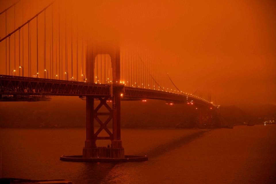 Cars drive along the San Francisco Bay Bridge under an orange smoke filled skyAFP via Getty Images