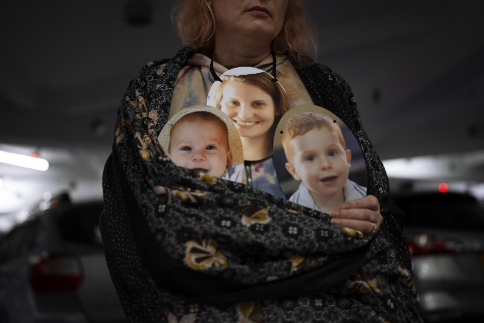 A woman holds a mask depicting the faces of Shiri Bibas and her sons Kfir and Ariel, Israelis who are being held hostage in the Gaza Strip by the Hamas militant group, during a protest demanding the release of the hostages from Hamas captivity, in Tel Aviv, Israel, Wednesday, Feb. 21, 2024. The activists participated in a performance called "Sorry we were kidnapped," Participants wore masks with the faces of hostages in a desperate plea to return the approximately 100 hostages still held in Gaza. (AP Photo/Oded Balilty)