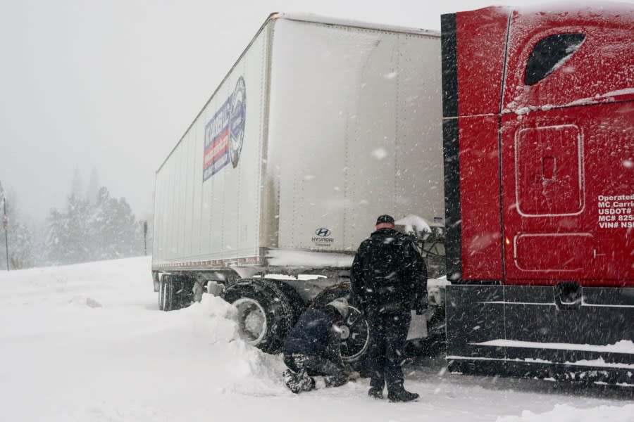 Chains are installed on a big rig’s tires during a storm, Saturday, March 2, 2024, in Truckee, Calif. A powerful blizzard howled Saturday in the Sierra Nevada as the biggest storm of the season shut down a long stretch of Interstate 80 in California and gusty winds and heavy rain hit lower elevations, leaving tens of thousands of homes without power. (AP Photo/Brooke Hess-Homeier)