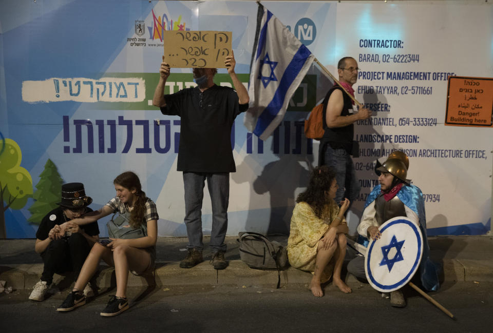 Israeli protesters hold signs during a demonstration against Israeli Prime Minister Benjamin Netanyahu outside his official residence in Jerusalem, Saturday, June 12, 2021. If all goes according to plan, Israel will swear in a new government on Sunday, ending Prime Minister Benjamin Netanyahu's record 12-year rule and a political crisis that inflicted four elections on the country in less than two years. (AP Photo/Ariel Schalit)