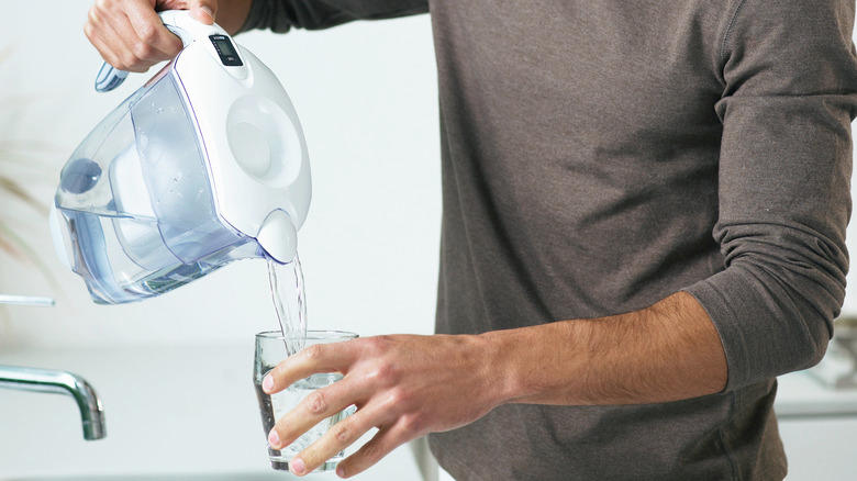 person pouring water filter