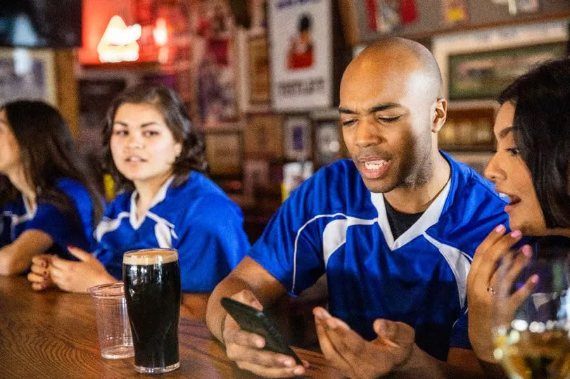 A group of sports fans watching the game at the bar