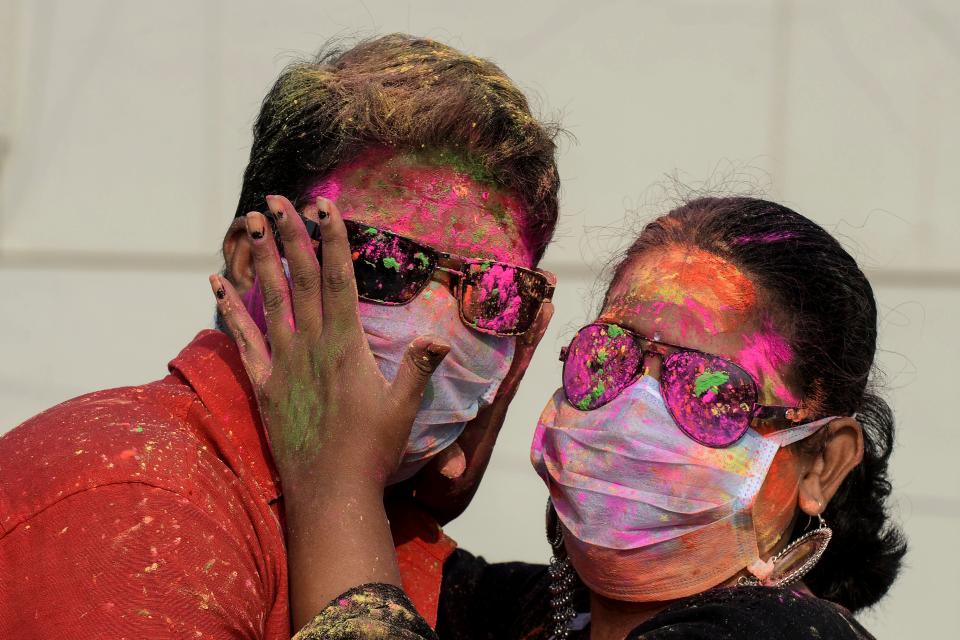 A couple wearing facemasks as a preventive measure against the COVID-19 coronavirus, apply smear their faces with coloured powder during a friends gathering the celebrate Holi.