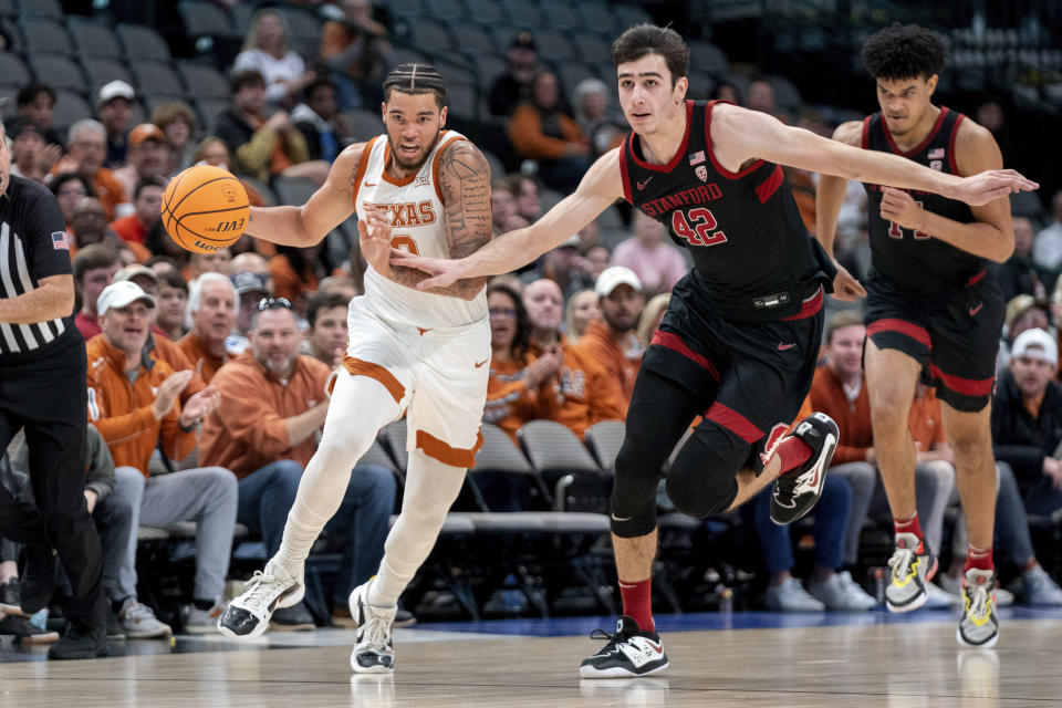 Texas forward Timmy Allen (0) drives past Stanford forward Maxime Raynaud (42) on a fast break during the first half of an NCAA college basketball game, Sunday, Dec. 18, 2022, in Dallas. (AP Photo/Jeffrey McWhorter)