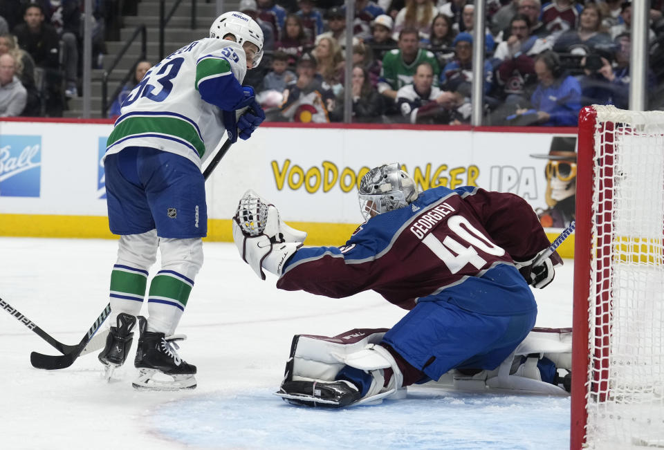 Colorado Avalanche goaltender Alexandar Georgiev, right, makes a glove save against Vancouver Canucks center Teddy Blueger during the second period of an NHL hockey game Wednesday, Nov. 22, 2023, in Denver. (AP Photo/David Zalubowski)