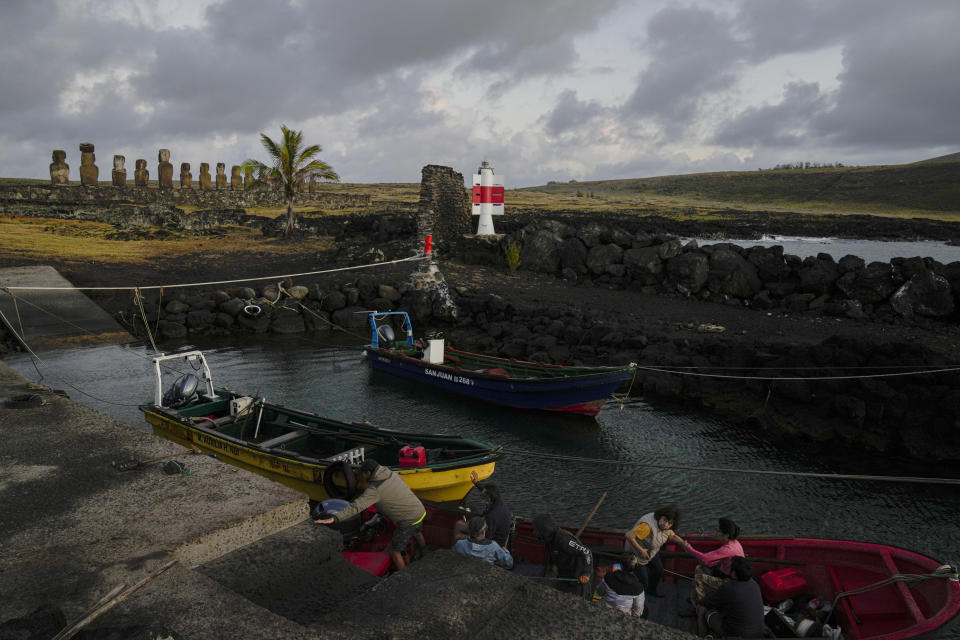 Fisherman Ariki Tepano arrives with tourists to the fishermen's cove near moais statues, top left, on Ahu Tongariki after giving a sightseeing tour of Rapa Nui, or Easter Island, Chile, Monday, Nov, 28, 2022. Each monolithic human figure carved centuries ago by this remote Pacific island's Rapanui people represents an ancestor. (AP Photo/Esteban Felix)