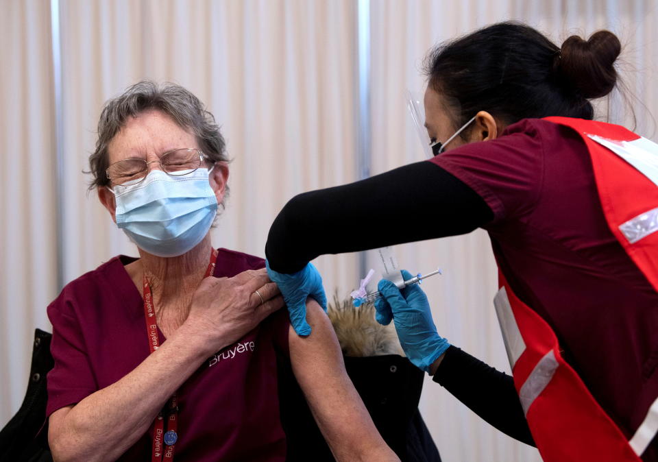 Personal support worker Johanne Lamesse reacts in anticipation to the needle as she receives the Pfizer-BioNTech COVID-19 vaccine at the Civic Hospital in Ottawa, Ontario, Canada December 15, 2020.  Adrian Wyld/Pool via REUTERS     TPX IMAGES OF THE DAY
