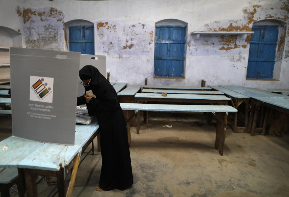 An Indian Muslim woman casts her vote inside a polling station in Varanasi, India, Sunday, May 19, 2019. Indians are voting in the seventh and final phase of national elections, wrapping up a 6-week-long long, grueling campaign season with Prime Minister Narendra Modi's Hindu nationalist party seeking reelection for another five years. Counting of votes is scheduled for May 23. (AP Photo/Rajesh Kumar Singh)